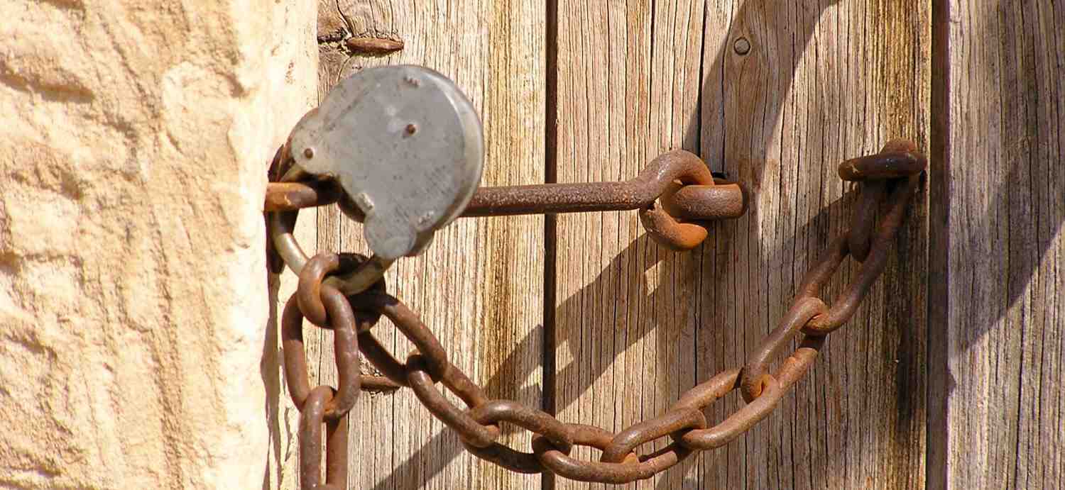 Vieille porte en bois fermée par une chaine rouillée et un cadenas